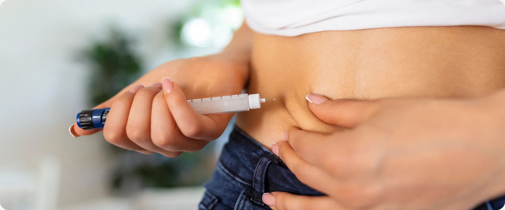 Pessoa aplicando caneta injetável na região abdominal