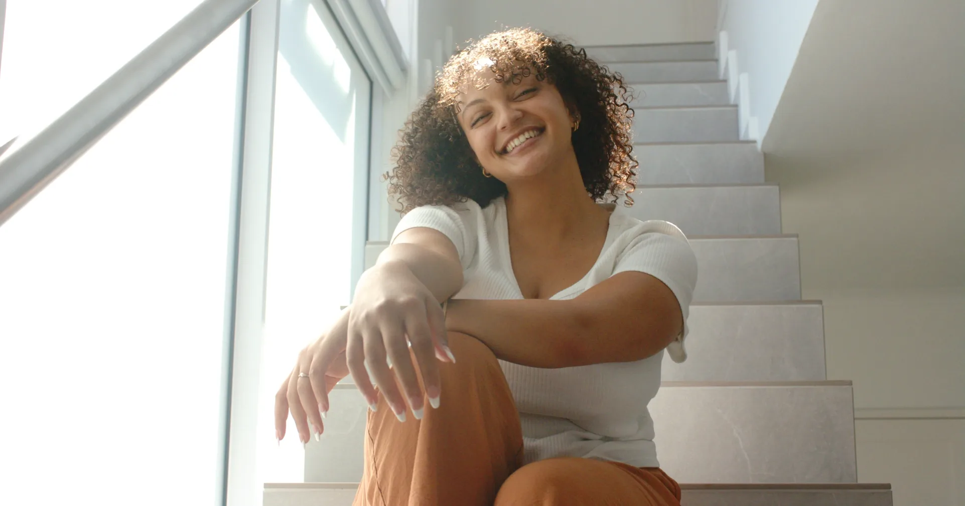 Mulher sorrindo sentada em uma escada