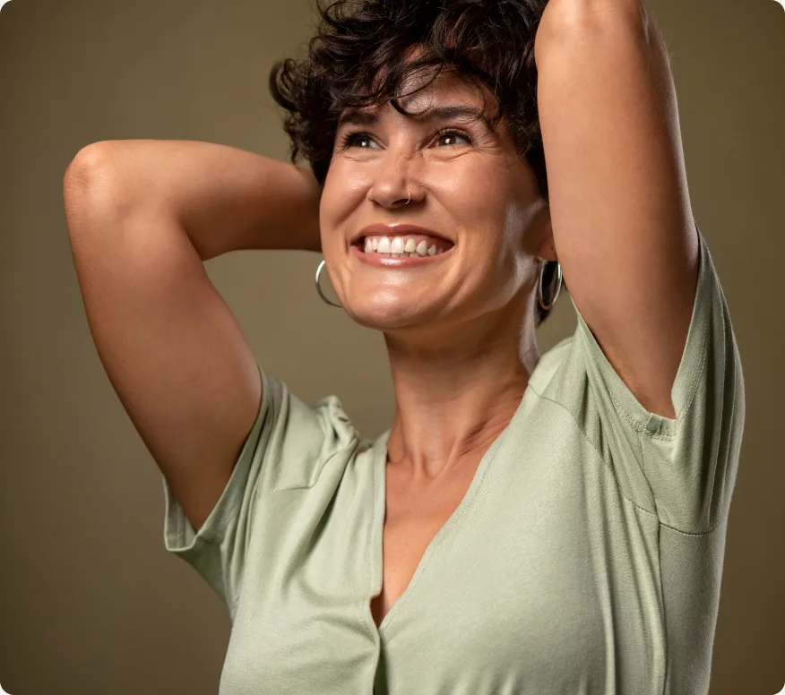Mulher sorrindo com os braços atrás da cabeça, demonstrando bem-estar e equilíbrio